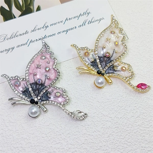 Macro shot of butterfly brooch with sparkling crystals, enamel wings and white pearl details