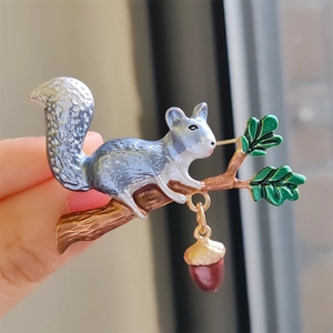 Cute squirrel brooch on a branch with green leaves and a brown acorn pendant charm
