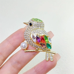 Detailed close-up of a colorful magpie bird brooch with crystals and a pearl accent
