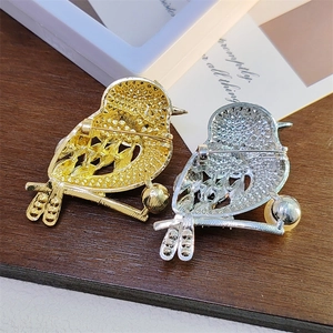Detailed view of magpie bird brooches in gold and silver finish with pearl accent