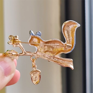 Macro detail of the squirrel brooch back featuring golden texture and safety pin clasp
