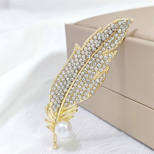 Elegant gold feather brooch with shimmering rhinestones and a central white pearl detail