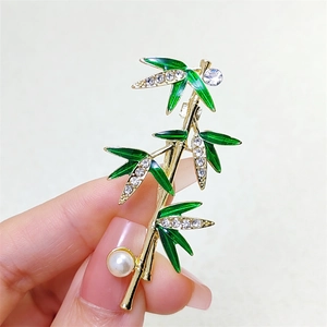 Elegant bamboo brooch with green enamel leaves, small diamonds, and a white pearl accent