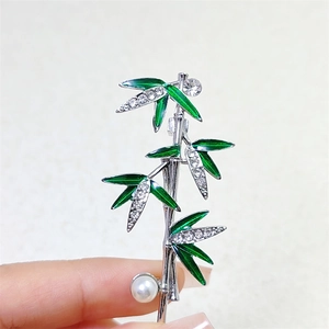 Elegant bamboo brooch with green enamel leaves, white pearl, and sparkling crystals