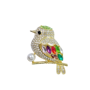 Elegant bird brooch in gold finish with colorful crystals and a white pearl detail