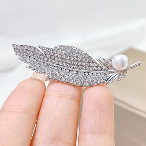 Elegant silver feather brooch with sparkling rhinestones and a white pearl detail