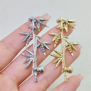 Macro detail of gold and silver bamboo brooches with crystals on a textured fabric