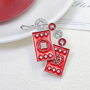 Festive red enamel brooch with rhinestones and Chinese character for wealth on a dish