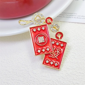 Close-up of a festive red enamel brooch with golden Chinese characters and crystals