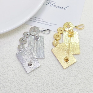 Close-up of dual-layer brushed metal brooches showing secure back pin locking mechanism