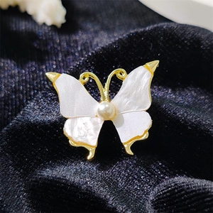 Luxurious gold butterfly brooch with white mother-of-pearl wings and a center pearl