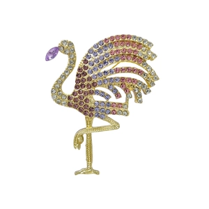Exquise broche flamant rose dorée avec strass dégradés rose et bleu sur fond blanc