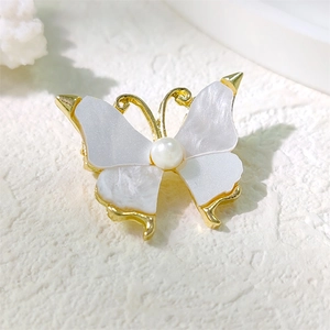 Elegant butterfly brooch in golden metal with mother-of-pearl wings and a white pearl