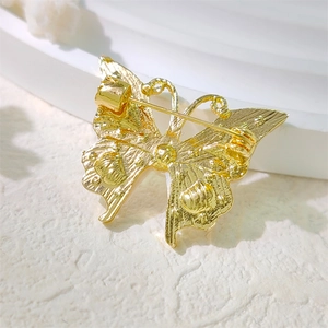 Detailed back view of golden butterfly brooch with secure pin lock and textured alloy surface
