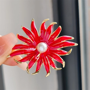 Broche tournesol rouge élégante avec perle centrale et contour doré tenue en main