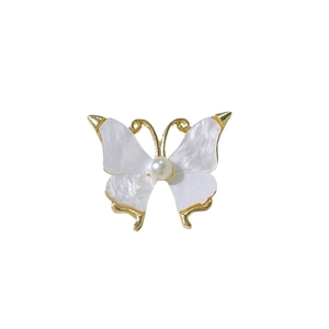 Elegant butterfly brooch with pearl center and golden edges on white background