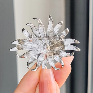 Vue détaillée d'une broche tournesol argentée avec texture en métal brossé et épingle