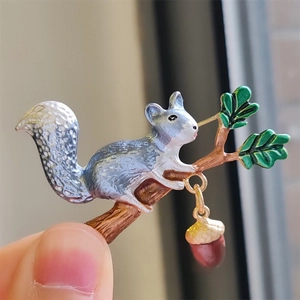 Cute Japanese squirrel brooch with green leaves and a red acorn in silver finish