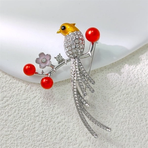 Exquisite magpie brooch with yellow enamel, rhinestones and red pearls on a floral branch