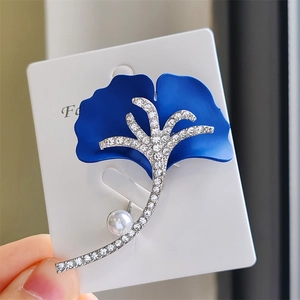 Détail d'une luxueuse broche feuille de ginkgo bleue avec cristaux et une perle