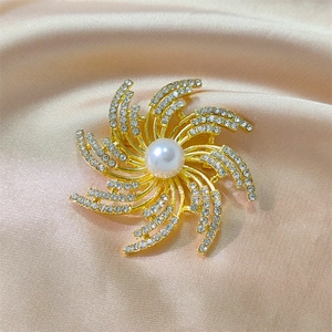 Broche en forme d'étoile dorée avec perle centrale et strass blancs sur satin