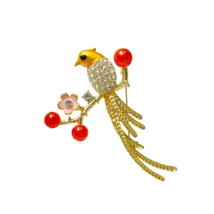 Elegant magpie bird brooch with sparkling rhinestones and red floral accents on gold finish