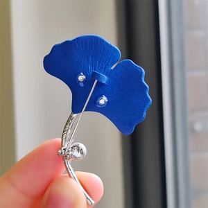 Gros plan sur la broche feuille de ginkgo bleu foncé avec des détails argentés élégants