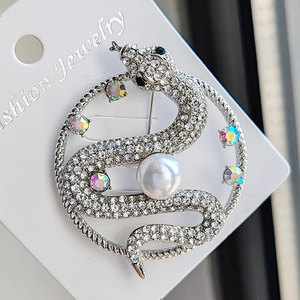 Silver snake brooch with sparkling rhinestones and a white pearl on a display card