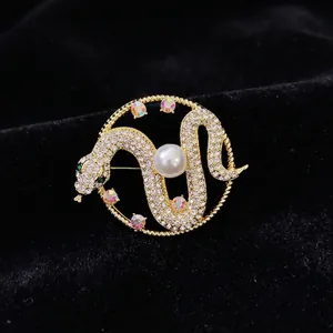 Luxurious snake brooch with white crystals and central pearl in gold finish