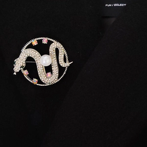 Vintage luxury silver snake brooch with inlaid pearls and sparkling crystals on black coat