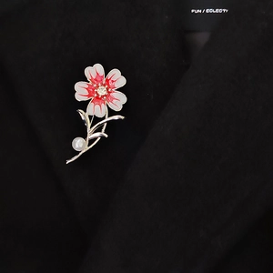 Detail der Blumenbrosche mit Emaille, Perle und Kristall am schwarzen Mantelaufschlag