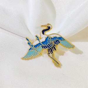 Exquisite crane enamel brooch in gold and blue finish on elegant white silk background