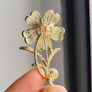 Makro-Detail der goldenen Blumenbrosche Rückseite mit Nadelverschluss und Metallstruktur