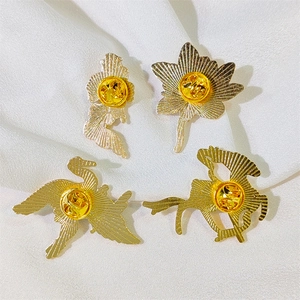Detailed back view of golden metal brooches with butterfly clasps and textured finish