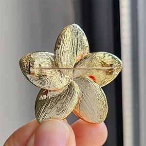 Macro view of the golden flower brooch back featuring a secure rotating safety pin
