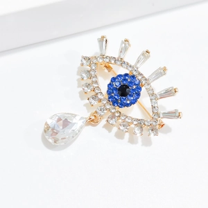 Luxurious Evil Eye brooch in gold finish with blue crystals and teardrop pendant
