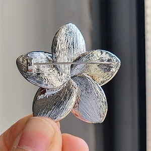 Detail of the silver five-petal flower brooch back with secure pin clasp and textured metal