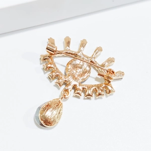Detail of the golden evil eye brooch showing the secure pin back and pear-shaped stone