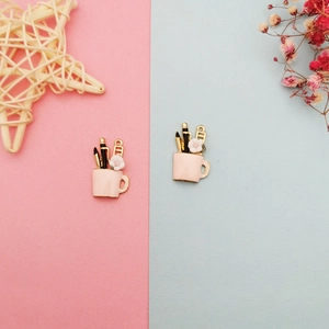 Detailed view of two pink miniature mug charms featuring stationery and white flower