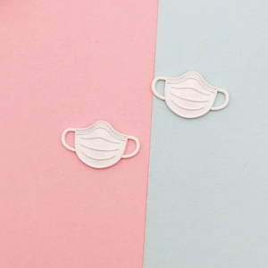 Detailed view of two off-white matte mask-shaped alloy charms for DIY jewelry making