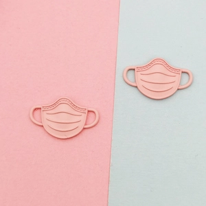 Detailed macro view of pink matte resin face mask charms for DIY jewelry and accessories