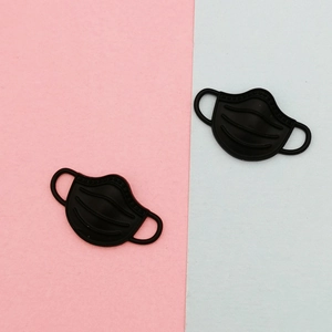 Detail showing two black matte alloy face mask charms for DIY jewelry and accessory crafts