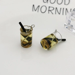 Makroaufnahme von Mini-Bubble-Tea-Anhänger aus Harz mit schwarzem Strohhalm und Goldglitzer