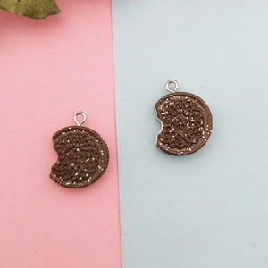 Détail d'un pendentif en résine biscuit chocolat avec morsure et anneau métallique