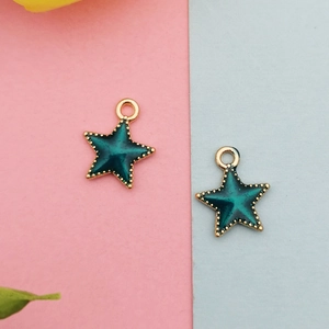 Detailed view of star-shaped alloy pendants with dark green enamel and gold-plated edges