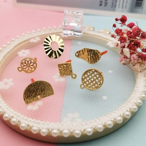 Goldenes DIY-Ohrring-Schmuckzubehör mit vielfältigen Texturen auf einem Spitzenhintergrund