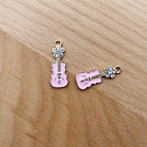 Detailansicht von zwei rosa Emaille-Gitarrenanhängern mit Goldlegierung und funkelnden Strass