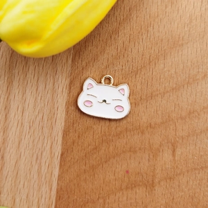 Details eines süßen weißen Emaille-Katzenanhängers für DIY-Schmuck auf Holzgrund