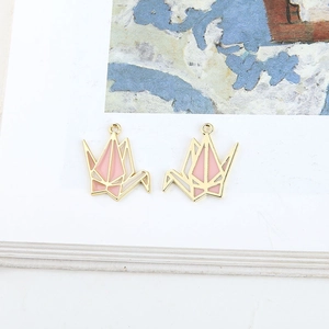 Macro detail of pair of pink enamel origami crane alloy charms for DIY jewelry making