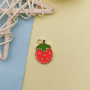 Détail d'un pendentif fraise en émail rouge avec bords dorés pour la création de bijoux DIY